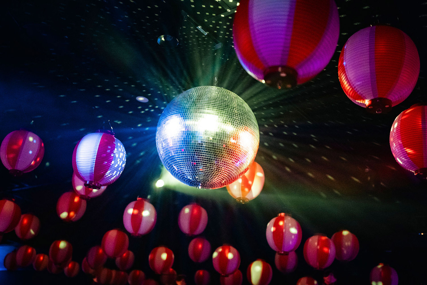 Disco ball reflecting colorful lights among hanging lanterns